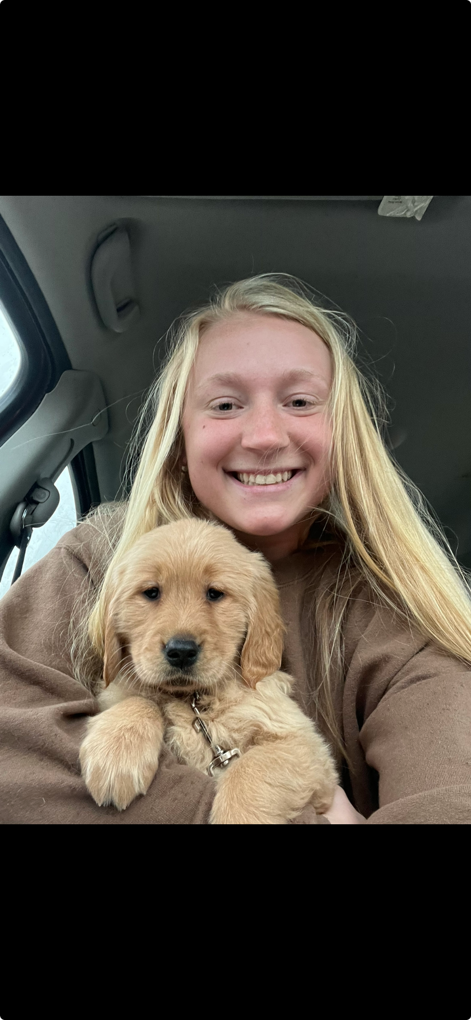 Kaley in a brown sweatshirt holding a puppy